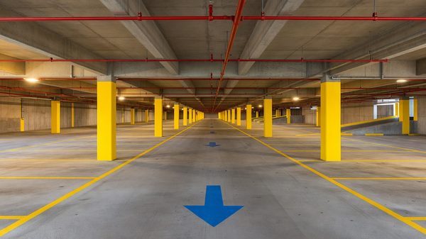 Interior of a multi-level concrete parking garage with marked bays and overhead lighting